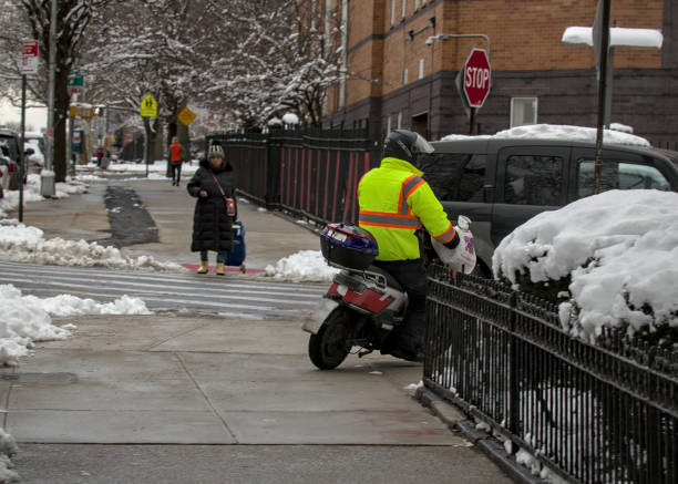 zusteller fährt mit einem elektromotorrad auf dem bürgersteig in brooklyn. - motorcycle snow winter new york city stock-fotos und bilder