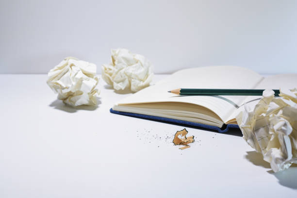 A notebook, paper, pen, calculator and other other personal finance tools are seen scattered on a desk in this at home finance concept.