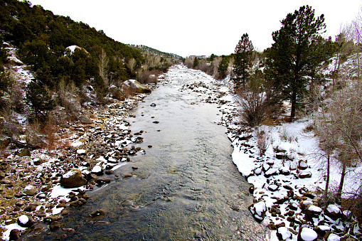 Snow covers the banks of the Arkansas River where it flows past Buena Vista, Colorado a popular white water rafting location in warmer months.