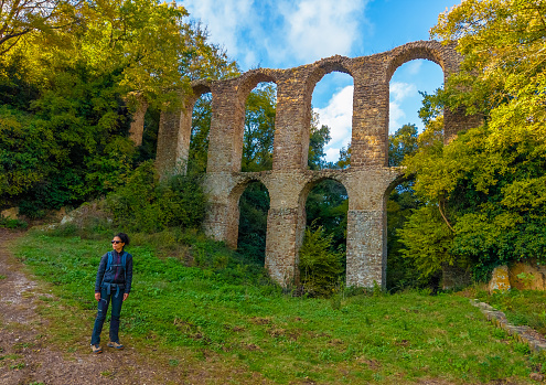 Tuscia, Italy - 5 November 2023 - The touristic area in province of Viterbo and Rome, with ancient village on the hill, ruins, forest and badlands, in the Lazio region. Here in particular a view of Faggeta of Antica Monterano old town with girl hiker