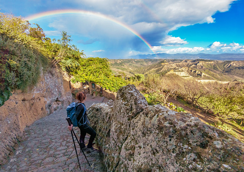 Tuscia, Italy - 5 November 2023 - The touristic area in province of Viterbo and Rome, with ancient village on the hill, ruins, forest and badlands, in the Lazio region. Here in particular a view of Civita di Bagnoregio town with girl hiker and rainbow