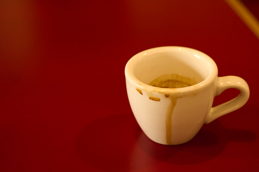 Coffee depression, empty coffee cup after drink with coffee stain of espresso on table. Cup of Espresso on a wooden table. Close up hot coffee Espresso in a white mug on red table background. Flat-lay, top view. Cup of coffee with pure black and brown. Copy space, food and drink concept.