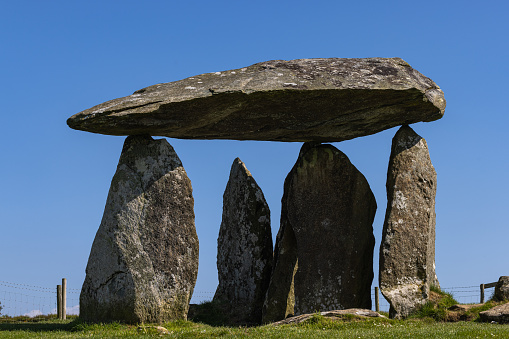 Pentre Ifan, United Kingdom - May 20, 2023: The giant capstone of the Neolithic burial chamber is perched on three vertical stones set against a clear blue sky in this 5000 year old stone age monument in South Wales.