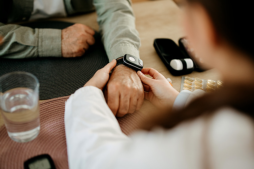 Woman from the medical health system wears a smartwatch for remote monitoring of vital signs on an elderly person