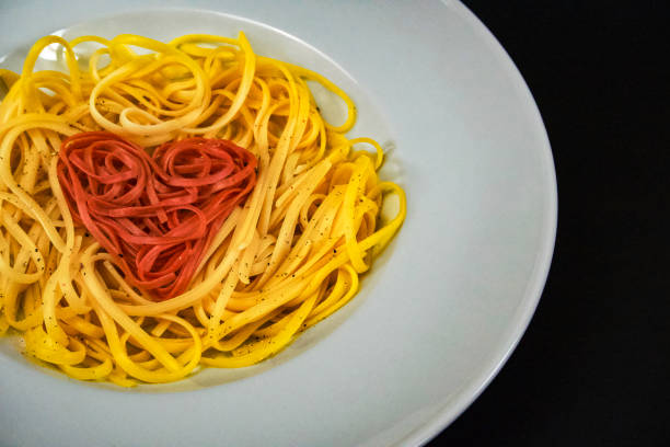 red linguine heart-shaped arranged - teigwaren foto e immagini stock