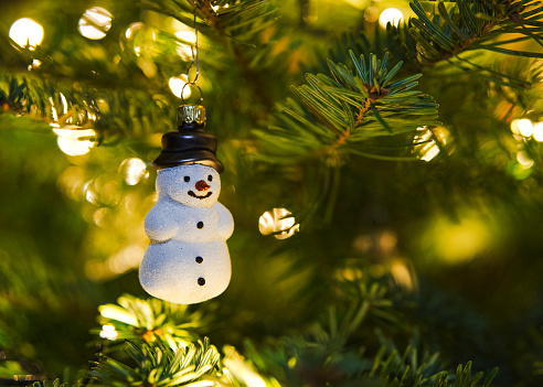 Glittering snowman Christmas tree pendant on the illuminated Christmas tree, horizontal