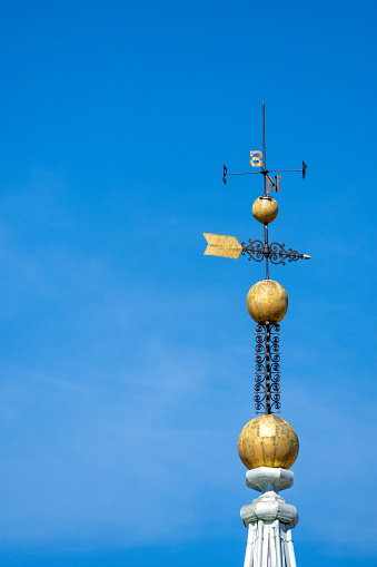 A golden weather vane against a blue sky with copy space. Symbol of direction.
