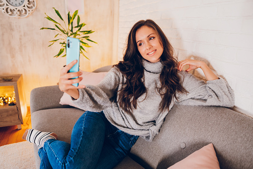 A young woman takes a selfie while enjoying at home.