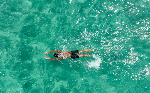 High angle view photo of a mid adult man swimming and relaxing in the ocean