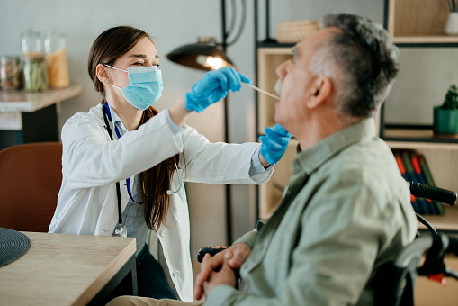 Doctor or nurse using a swab to take a sample from a senior patient's throat.