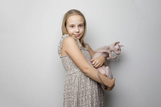 Cute kid hugging cat against gray studio wall banner background