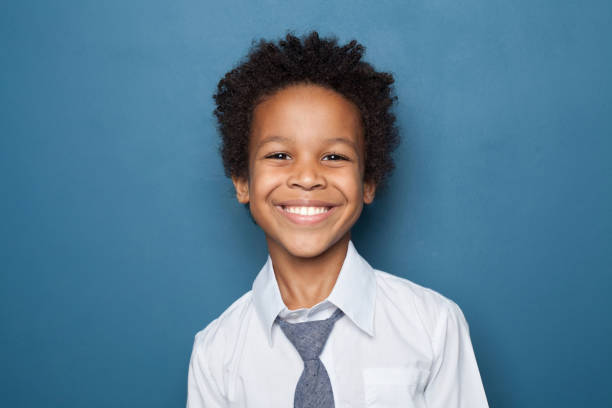 Handsome successful child boy with cute smile wearing white shirt posing on blue background