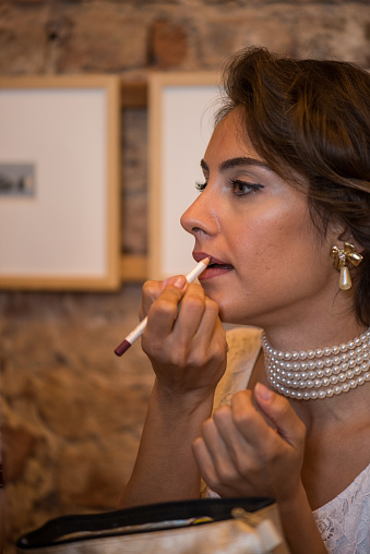 Close-Up Portrait of woman applying lipstick on her lip