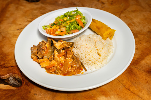 Beef goulash with rice, slice of ripe banana and vegetable salad