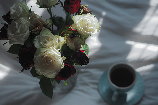 A bouquet of flowers with a cup and sheet on a table