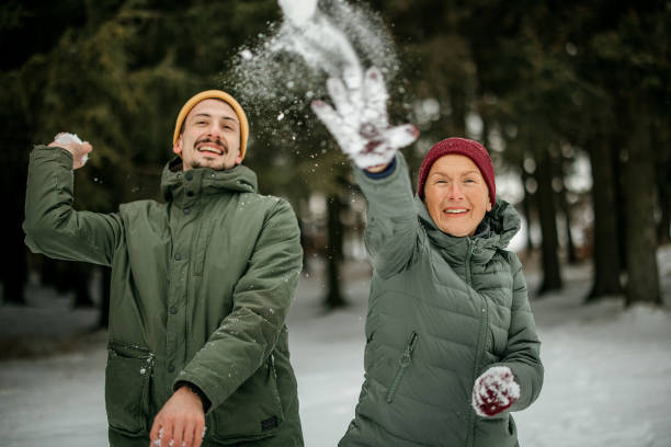 Smiling men wearing winter clothes and throwing snowball into air.