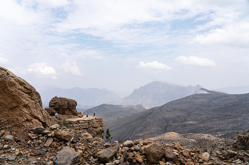 Spectacular dirt road through Wadi Bani Awf—one of Oman’s most picturesque valley. In distance pair of unrecognizable persons at the edge of a cliff.