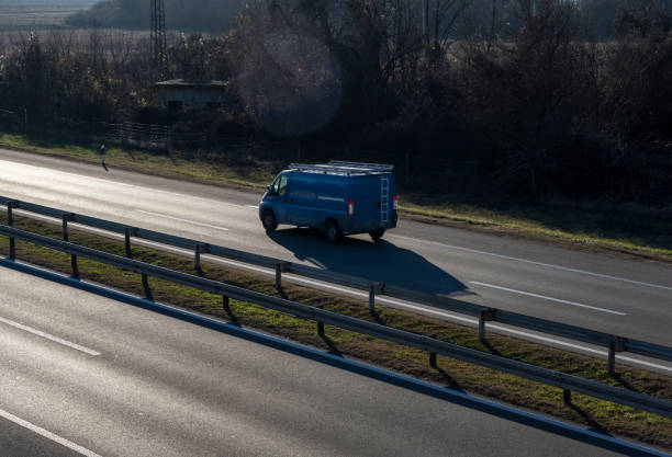 Blue modern delivery small shipment cargo courier van moving fast on motorway road to city urban suburb