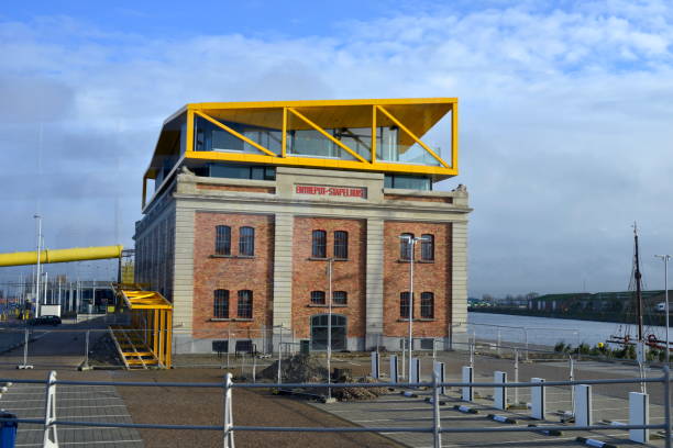 Modern building under construction with red steel beams and blue scaffolding against a clear blue sky