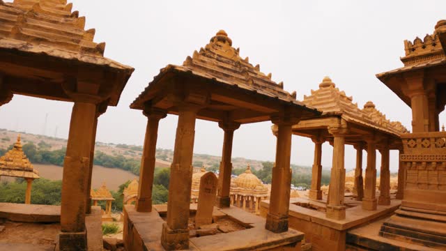 4K moving shot of old historical cenotaphs of Bada Bagh at Jaisalmer, Rajasthan, India. Ancient Indian architecture. Exploring heritage sites of India. Royal Chhatris made from yellow sandstone