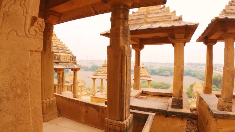 4K moving shot of pillars of the cenotaphs and Royal Chhatris in Thar desert at Jaisalmer, Rajasthan, India. View of desert from inside cenotaphs of Bada Bagh. Historical Indian architecture.