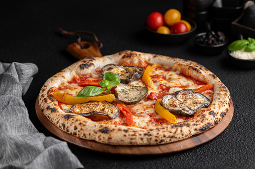 Freshly baked pizza with various toppings on a rustic wooden serving board