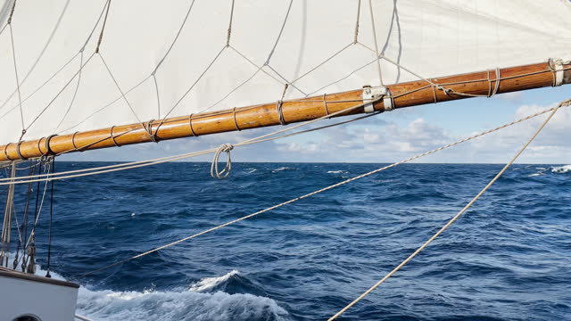 view from a retro style sailing schooner during the passage of the Drake Strait, wooden boat boom, lots of ropes, large waves of the southern ocean in sunny weather