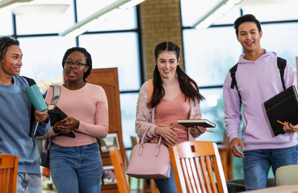 istock Four multiracial high school students walking in library 2023139143