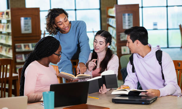 Four multiracial high school students studying in library