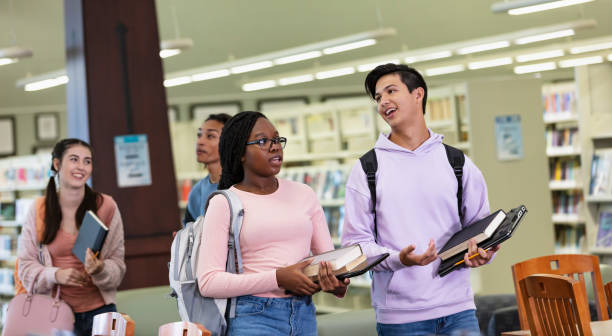 istock Four multiracial high school students walking in library 2023139716