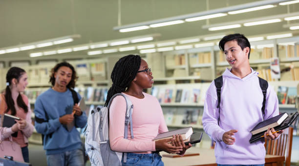 istock Four multiracial high school students walking in library 2023140223