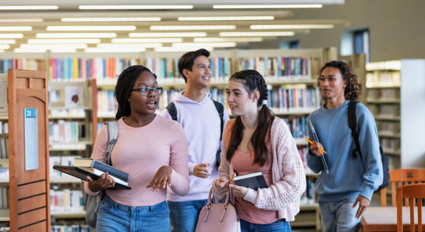 istock Four multiracial high school students walking in library 2023140226