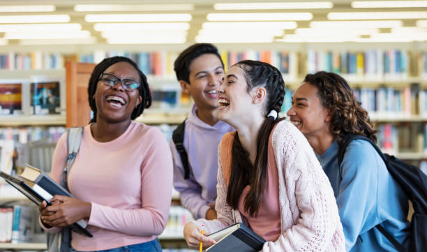 Multiracial high school students walk in library, laughing