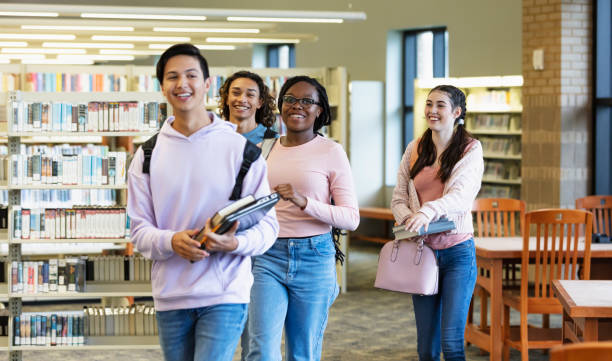 istock Four multiracial high school students walking in library 2023140239