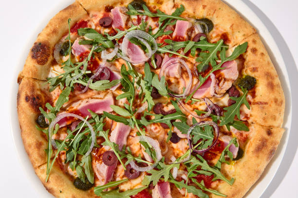 Deluxe NiÃ§oise-Style Tuna Pizza with Olives and Arugula Overhead Shot Deluxe NiÃ§oise-Style Tuna Pizza with Olives and Arugula Overhead Shot. pizza topping stock pictures, royalty-free photos & images