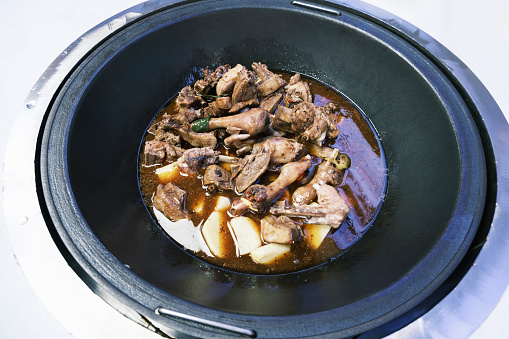 Duck meat is cooked in a large black iron pot