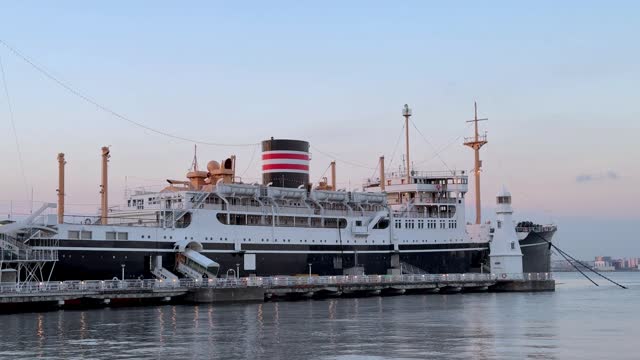 Vintage ocean liner docked at port during twilight, calm water with pastel sky