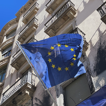 Blue EU flag with yellow stars on the background of a building