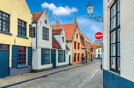 Bruges cityscape with empty narrow cobblestone street, colorful buildings, traditional houses in Brugge city historical centre, Bruges old town Steenstraat quarter, West Flanders province, Belgium