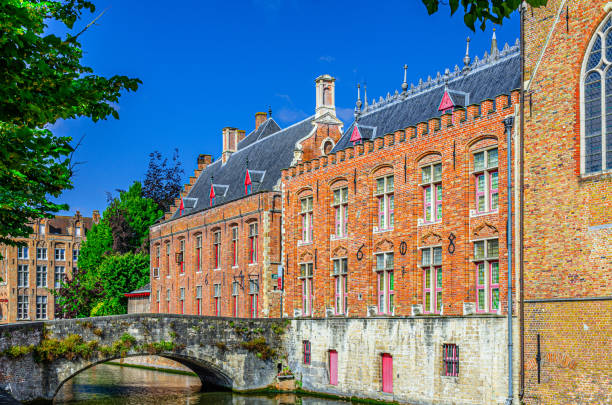 Blinde-Ezelbrug stone bridge across Groenerei Green Canal water of Reie river in Brugge old town, Brugse Vrije Liberty of Bruges Renaissance architecture style building in Bruges city center, Belgium puente de piedra blinde-ezelbrug sobre el agua del canal verde groenerei del río reie en el casco antiguo de brujas, brujas vrije libertad de brujas edificio de estilo arquitectónico renacentista en el centro de la ciudad de brujas, bélgica