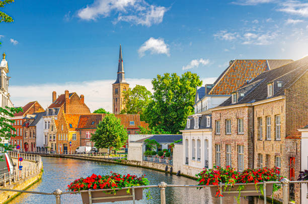 Bruges cityscape, Sint Annarei water canal, houses buildings on promenade in Brugge old town, flowers pots on fence, Bruges city historical centre, Saint Anna Church tower, Flemish Region, Belgium paisaje urbano de brujas, canal de agua de sint annarei, edificios de casas en el paseo marítimo del casco antiguo de brujas, macetas en la valla, centro histórico de la ciudad de brujas, torre de la iglesia de santa ana, región flamenca, bélgica