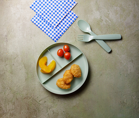 Kid's meal on a child's plate with fruit and vegetable