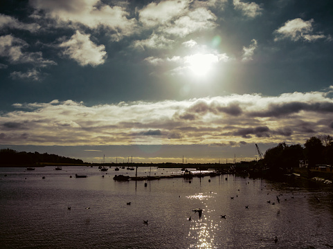 A view of the River Deben at Woodbridge in Suffolk, Eastern England, during a late afternoon in November with low sunlight causing a silhouetted effect.