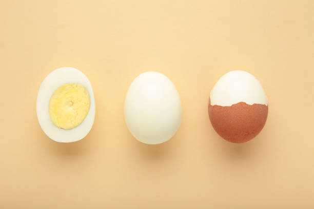 istock Whole white egg and halved boiled egg with yolk on beige background. 2023249968