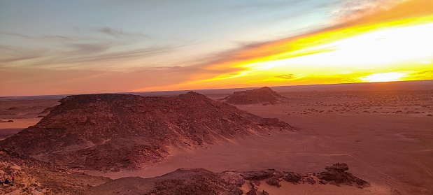 Panoramic sunset view from Timimoun, Algeria, overlooking the red sand desert and canyons from a hilltop. Petit Tassili.