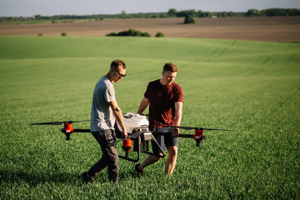 farmer with drone walking beside grass silage crop in field. - aero imagens e fotografias de stock