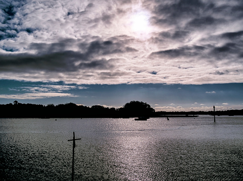 Deep shadows and bright sun with a dramatic sky over the River Deben in Woodbridge, Suffolk, Eastern England, late on a November afternoon.