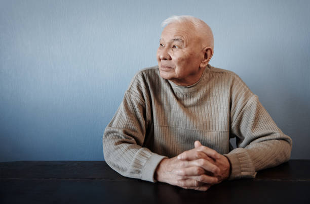 istock Pensive and thoughtful senior man sitting at the table 2023277977