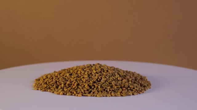 Heap of Fenugreek Seeds or Shambhala or helba. Trigonella foenum-graecum seeds used in food, drink and alternative medicine. Ayurvedic food. 4K video, Rotating