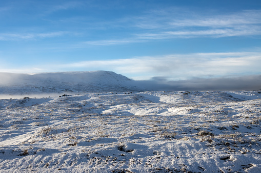 Arctic winter started in the autumn and covered the land by snow. Becuase of the waterfall air is full of steam and fog, partly hiding the mountains in the background. Fossholl - Godafoss, Iceland.